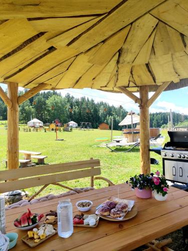 a wooden table with plates of food on it at Glamping Niebiańska Osada Jurty Dolnośląskie & SPA in Polanica-Zdrój