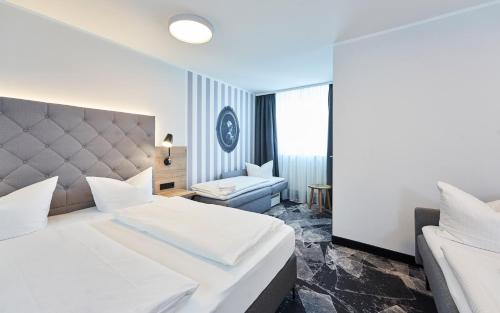 a hotel room with two beds and a couch at Das Landhotel am Trätzhof Fulda in Fulda