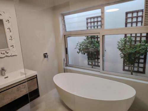 a bathroom with a white tub and a window at Sixteen Guesthouse on Main in Hermanus