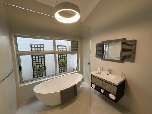 a bathroom with a large tub and a sink at Sixteen Guesthouse on Main in Hermanus