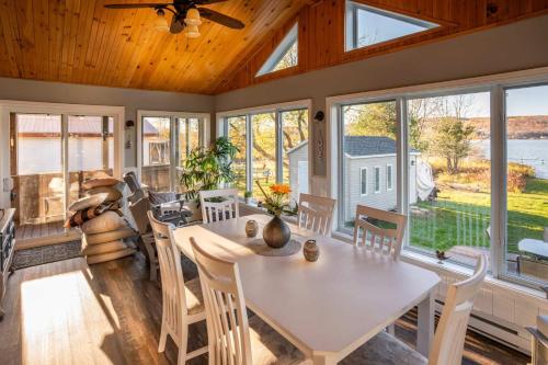 a dining room with a table and chairs and windows at Lake Nature & Outdoor Fun - Chalet Mandeville II in Mandeville