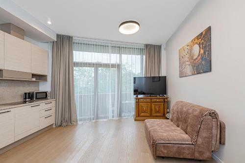 a living room with a couch and a flat screen tv at Saulės Sonata apartamentai 5 in Druskininkai