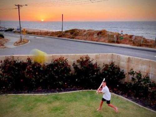 a man is swinging a baseball bat at the beach at Pet-Friendly Beachfront Family Dog Bch in Mandurah