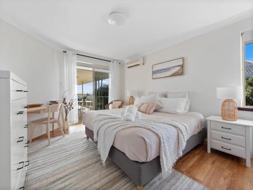 a white bedroom with a large bed and a desk at Pet-friendly Beachfront Family Retreat in Mandurah