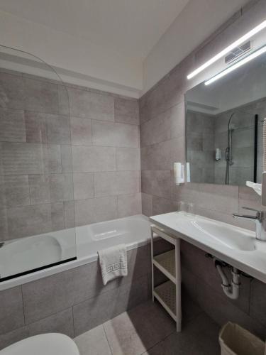 a bathroom with a tub and a sink and a mirror at Medos Hotel in Budapest