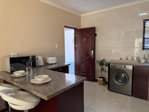 a kitchen with a counter with a washer and dryer at 25 Lillies in Rustenburg