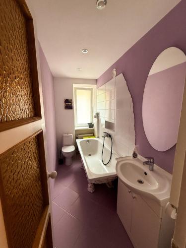 a purple bathroom with a sink and a toilet at Piejūras laivinieks in Liepāja