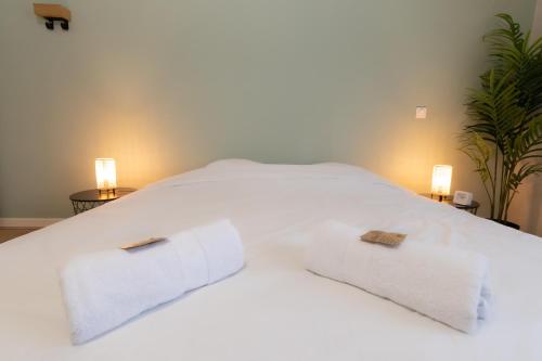 a white bed with two towels on top of it at Appart'Hotel Tournusien in Tournus