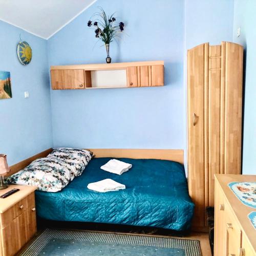 a small bedroom with a bed with a blue wall at Tawerna Murena in Poddąbie