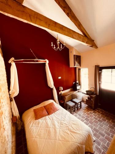 a bedroom with a bed and a red wall at Mini gîte royal in Sainte-Gemme-la-Plaine
