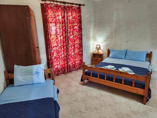 a bedroom with two beds and a window with a curtain at Akrata Golden Beach House in Aíyira