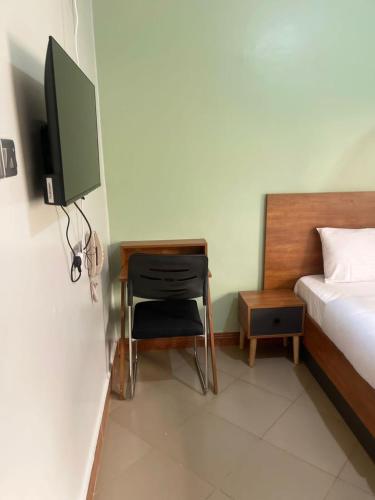 a bedroom with a desk and a bed and a television at Astro Motel in Nalakonge