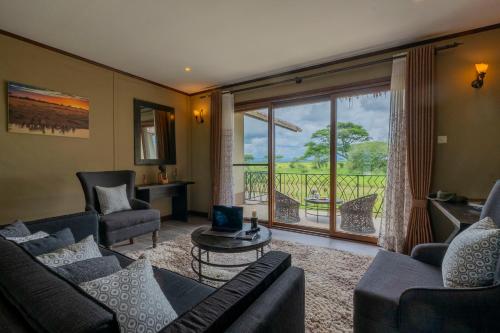 a living room with a couch and chairs and a window at Serengeti Sametu Camp in Serengeti National Park