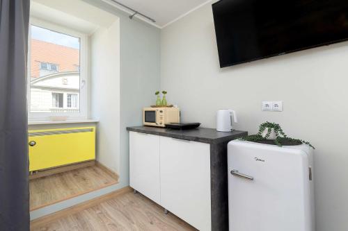 a small kitchen with a refrigerator and a microwave at Komfortowe Studio w Centrum Bytomia Blisko Rynku by Noclegi Renters in Bytom