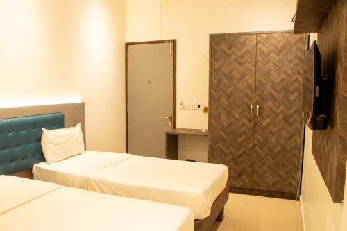 a hotel room with two beds and a door at J R Residency in Navi Mumbai