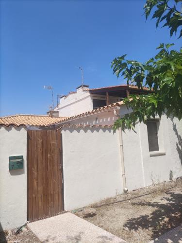 a white house with a wooden gate on the side of it at MAISON LEUCATINE - Classée 4 étoiles ! BBQ & Terrasse Privée - Climarisation & Parking privé - Séjour PROCHE PLAGE et IDEAL Famille - OFFRE SPECIALE - in Leucate-Plage