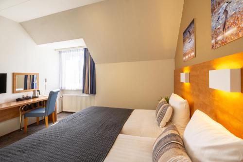 a hotel room with a bed and a desk at Hotel De Boei in Egmond aan Zee