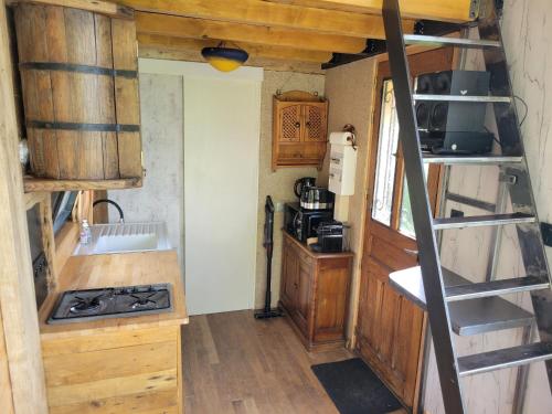 a small kitchen with a stove and a ladder at Tiny House La Chevêchette in Besson