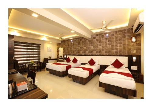 a hotel room with four beds and a desk at Hotel Kochi Caprice in Cochin