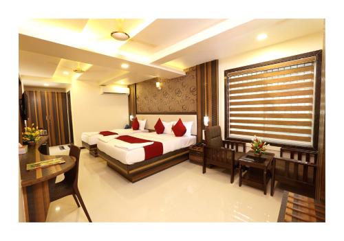 a hotel room with a bed and a desk and a bed and a room at Hotel Kochi Caprice in Cochin
