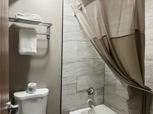 two pictures of a bathroom with a toilet and a shower at Studio 6 Ogden, UT 21st Street in Ogden