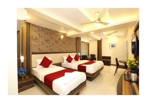 two beds in a hotel room with red pillows at Hotel Kochi Caprice in Cochin