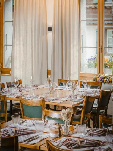 a dining room with tables and chairs with wine glasses at Hôtel de Commune - Rougemont in Rougemont