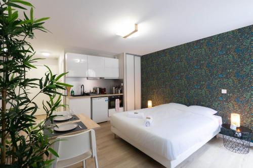 a bedroom with a white bed and a kitchen at Appart'Hotel Tournusien in Tournus