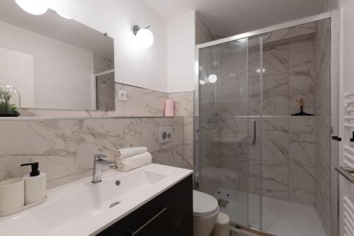 a bathroom with a sink and a glass shower at Appart'Hotel Tournusien in Tournus