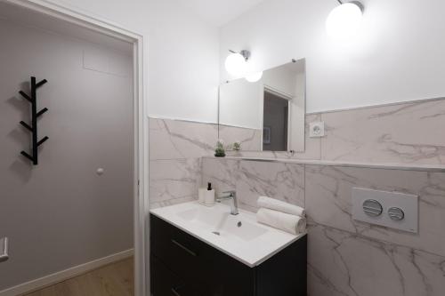 a white bathroom with a sink and a mirror at Appart'Hotel Tournusien in Tournus