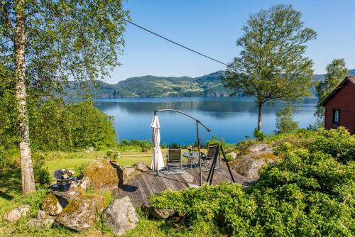 vistas a un lago con mesa y sombrilla en Nice House by the Sea with private beach and jetty, en Hjelmeland