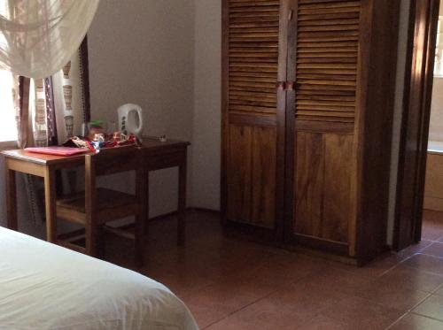 a bedroom with a desk and a closet and a bed at Tabonina Guesthouse in Livingstone