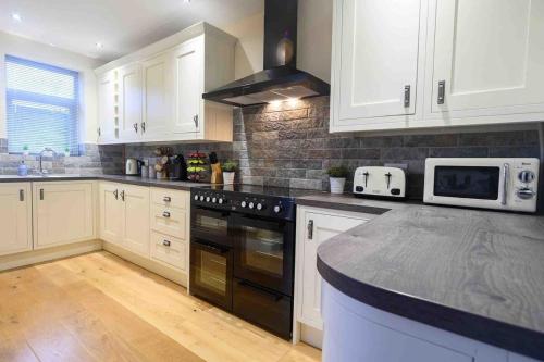 a kitchen with white cabinets and a black stove top oven at Beechwood House by Tŷ SA - ICC & Celtic Manor in Newport