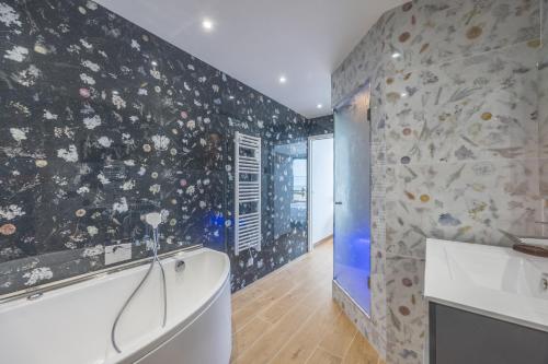 a bathroom with a white tub and a stone wall at Le penthouse des ours in Courseulles-sur-Mer