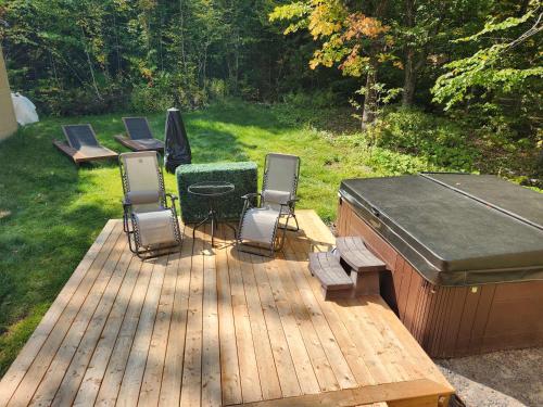 eine Holzterrasse mit Stühlen und einem Whirlpool in der Unterkunft Nature Comfort & SPA - Chalet Moderno in Sainte Brigitte de Laval