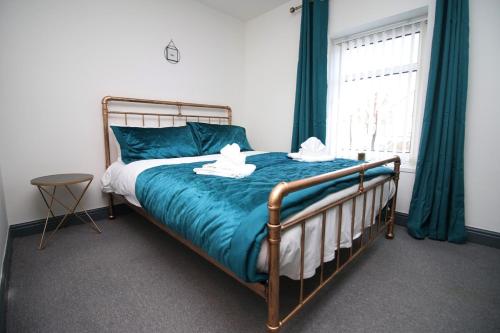 a bedroom with a bed with blue sheets and a window at Junctions Way by Tŷ SA -3 bed in Newport in Newport