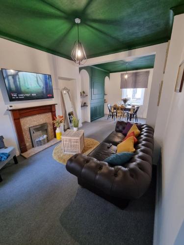 a living room with a leather couch and a flat screen tv at Junctions Way by Tŷ SA -3 bed in Newport in Newport