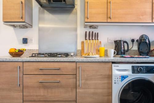 a kitchen with a stove and a washing machine at Ariel Wharf by Tŷ SA in Newport