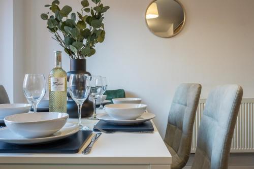 a dining room table with glasses and a bottle of wine at Ariel Wharf by Tŷ SA in Newport