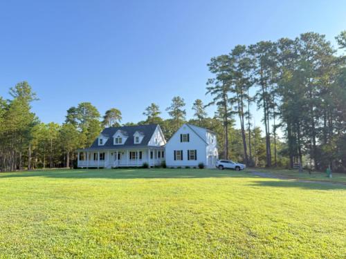 a white house with a car parked in a field at Serenity in White Stone