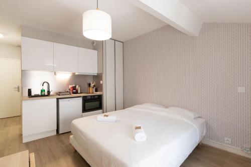 a bedroom with a white bed and a kitchen at Appart'Hotel Tournusien in Tournus
