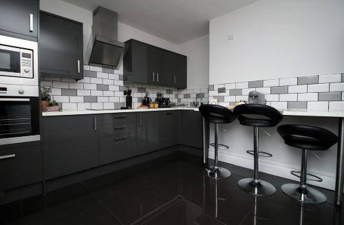 a kitchen with two bar stools and a microwave at Stunning sea views - Barry's Retreat by Tŷ SA in Barry