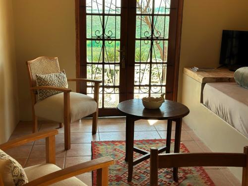 a living room with a table and a chair and a window at Dagbreek Cottages in Keimoes