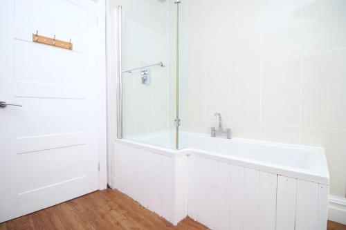 a white bathroom with a shower and a tub at Stunning sea views - Barry's Retreat by Tŷ SA in Barry
