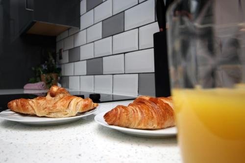 two plates of croissants and a glass of orange juice at Stunning sea views - Barry's Retreat by Tŷ SA in Barry