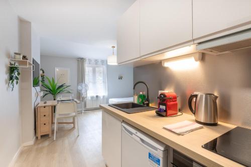 a kitchen with white cabinets and a counter top at Appart'Hotel Tournusien in Tournus