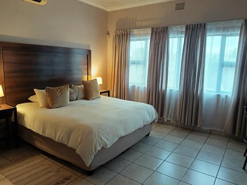 克莱克斯多普Andante Guesthouse Klerksdorp的卧室配有一张带白色床单和窗户的大床。
