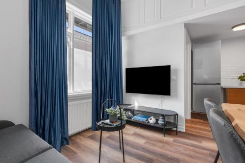 a living room with a television and blue curtains at Berg Apartments in Reykjavík