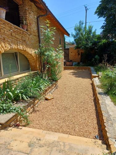 a garden with a gravel path next to a brick house at Gite dans maison médiévale Calme Fibre 2 ch in Jarnioux