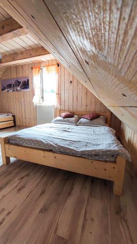 a bed in a room with a wooden ceiling at Cifrovaná drevenička in Detva